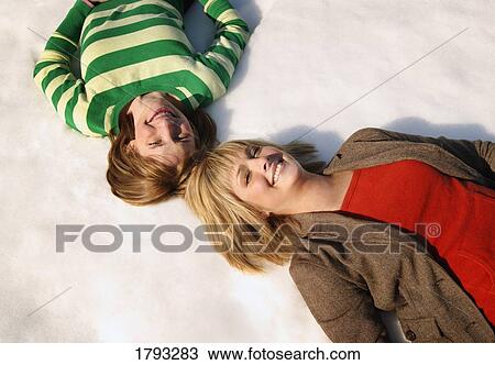 Stock Image - Mother and daughter laying on snow. Fotosearch