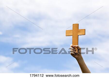 Stock Image - Person holding up a cross. Fotosearch