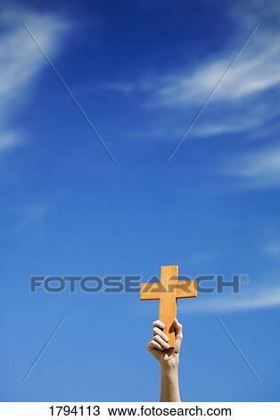 Stock Image - Person holding up a cross. Fotosearch
