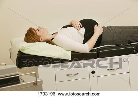 Pregnant woman laying in doctor's office View Large Photo Image Stock Photograph - Pregnant woman laying in doctor's office. Fotosearch