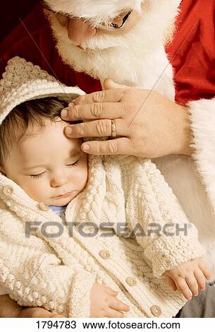 Stock Image - Santa Claus holding a baby. Fotosearch