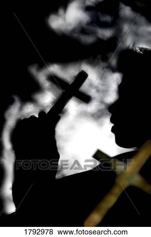 Silhouette of person holding cross View Large Photo Image Stock Photo - Silhouette of person holding cross . Fotosearch
