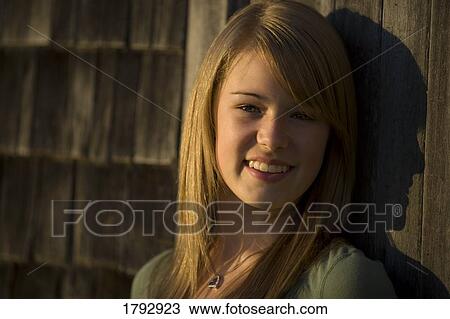 Stock Image - Teenage girl leaning on older building. Fotosearch