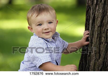 Stock Photograph - Toddler beside tree trunk. Fotosearch