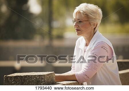 Stock Image - Woman leaning on fence. Fotosearch
