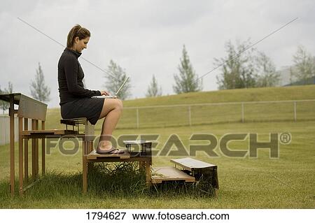 Stock Photo - Woman with laptop on bleachers. Fotosearch