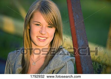 Stock Image - Young woman beside old metal structure. Fotosearch