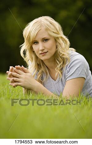 Young woman laying on grass View Large Photo Image Stock Image - Young woman laying on grass. Fotosearch