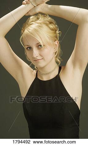 Stock Image - Young woman posing with arms over head. Fotosearch