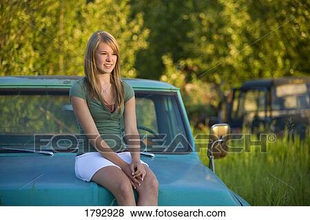 Young woman sitting on hood of old truck View Large Photo Image Stock Photo - Young woman sitting on hood of old truck. Fotosearch