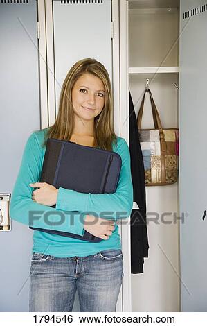 Young woman standing by locker View Large Photo Image Stock Photograph - Young woman standing by locker. Fotosearch