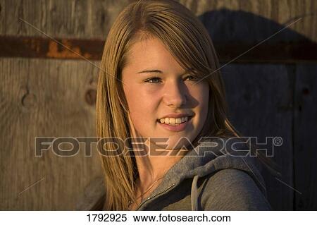Young woman stands against old wooden building View Large Photo Image Stock Photography - Young woman stands against old wooden building. Fotosearch