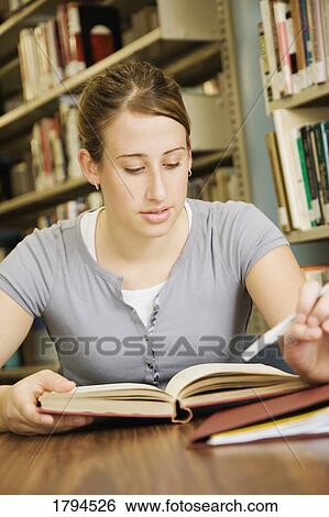 Stock Photograph - Young woman studying in library. Fotosearch