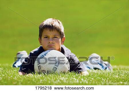 Stock Photo - Boy resting with soccer ball. Fotosearch