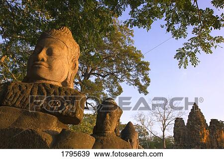 Head statues and distant ruins, Angkor Wat Temple Complex, Angkor Thom, Cambodia View Large Photo Image Stock Photo - Head statues and distant ruins, Angkor Wat Temple Complex, Angkor Thom, Cambodia. Fotosearch