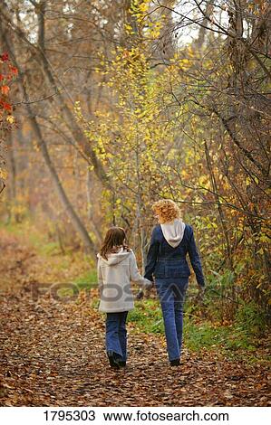 Stock Image - Mother and daughter walking down path. Fotosearch