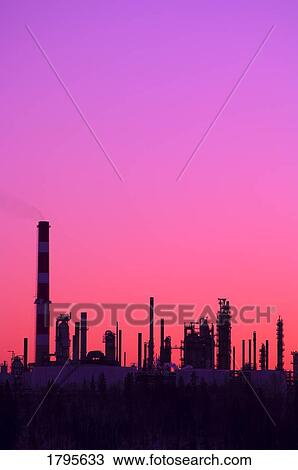 Stock Image - Silhouetted refineries in front of pink and purple sky. Fotosearch