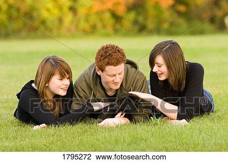 Stock Image - Teenagers petting a dog. Fotosearch