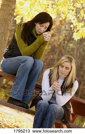Stock Image - Two women praying. Fotosearch