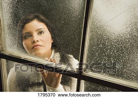 Stock Image - Woman looking out a window. Fotosearch