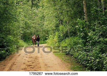 Stock Photo - Woman walking her horse. Fotosearch