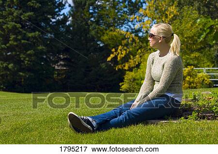 Stock Photo - Young woman sitting in the grass. Fotosearch