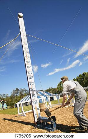 Stock Photograph - Man hitting the high striker. Fotosearch