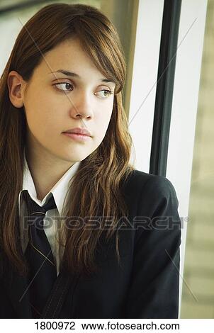 Stock Image - A student in uniform, looking out a window. Fotosearch