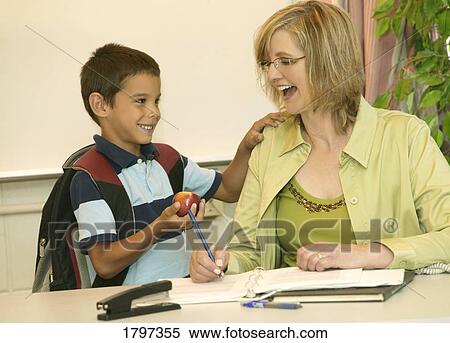 A young boy giving an apple to his teacher View Large Photo Image Stock Photography - A young boy giving an apple to his teacher. Fotosearch