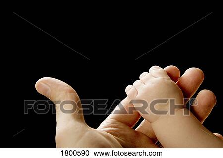 Stock Image - Baby hand grasping adult finger. Fotosearch