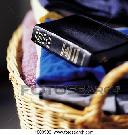 Stock Image - Bible on top of laundry folded in basket. Fotosearch