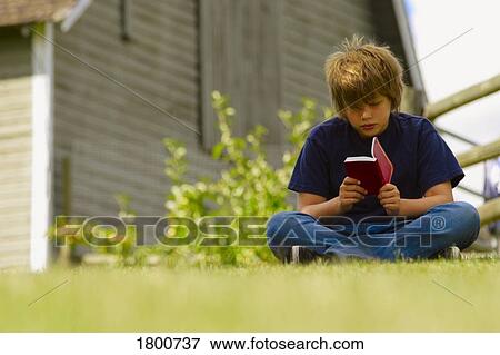 Stock Photo - Boy reading a book outside. Fotosearch