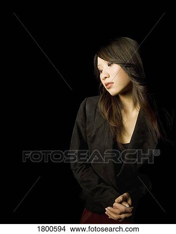 Picture - Brunette female standing with hands clasped. Fotosearch
