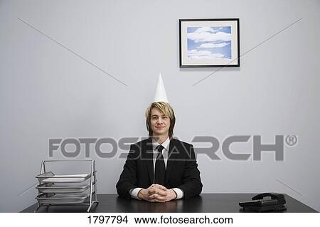 Picture - Businessman wearing a dunce cap. Fotosearch