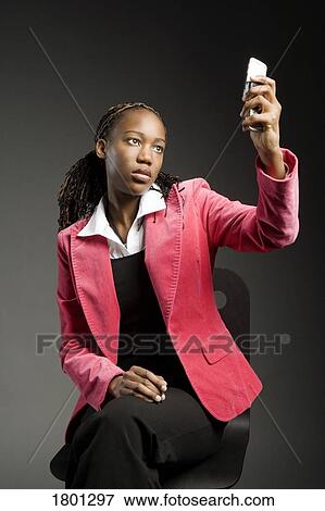 Stock Photo - Businesswoman looking at her cell phone with a frown. Fotosearch