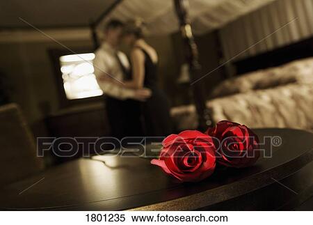 Stock Photography - Couple embracing with roses on table. Fotosearch