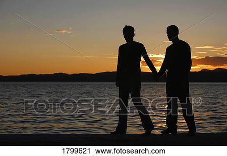 Stock Image - Couple walks along the beach. Fotosearch