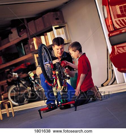 Stock Photo - Father and son working on bike. Fotosearch