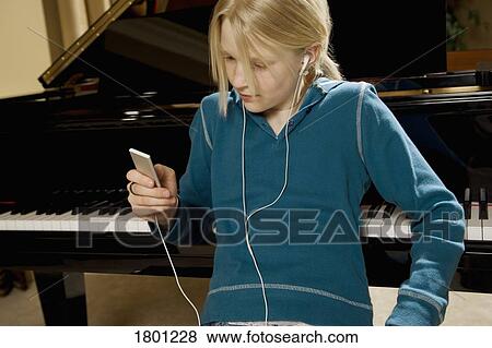 Stock Photo - Girl listening to music sitting at a piano. Fotosearch