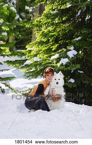 Picture - Girl sitting with dog in snow. Fotosearch