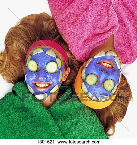 Stock Image - Girls with cucumber and face mask. Fotosearch