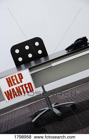 Stock Photo - Help wanted sign hanging off a desk. Fotosearch