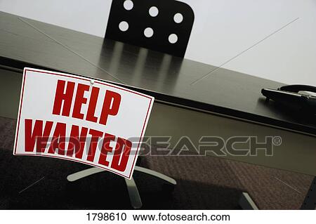 Stock Image - Help wanted sign on a desk. Fotosearch