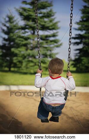 Stock Image - Little boy alone on a swing . Fotosearch