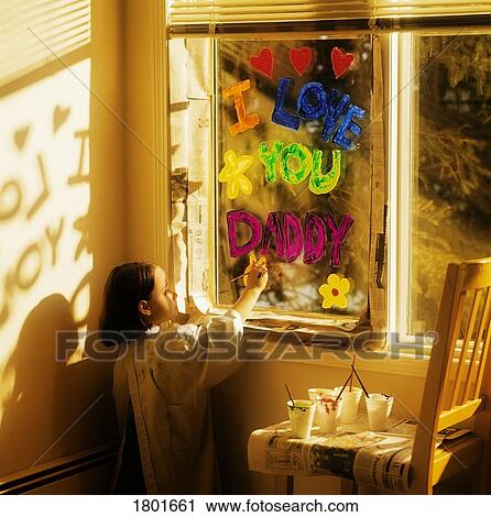 Stock Image - Little girl painting 'I love you daddy' on window. Fotosearch