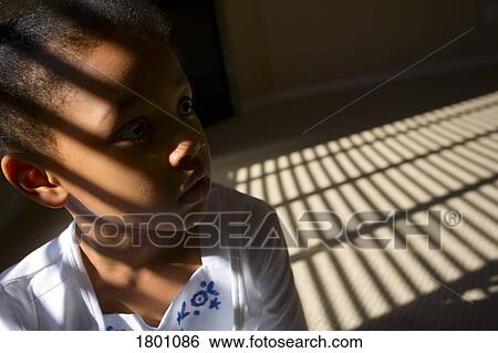 Stock Photograph - Little girl with light reflecting on face through window. Fotosearch