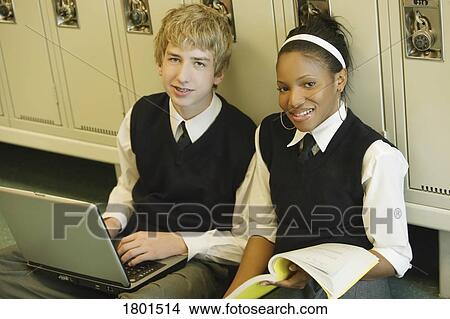 Picture - Male and female private school students sitting in hallway with laptop. Fotosearch