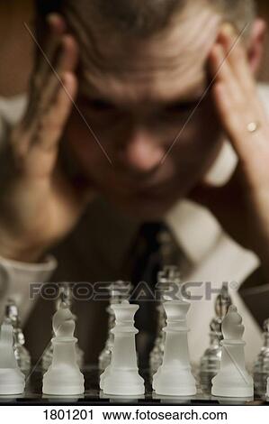 Stock Image - Man concentrating on chess game. Fotosearch