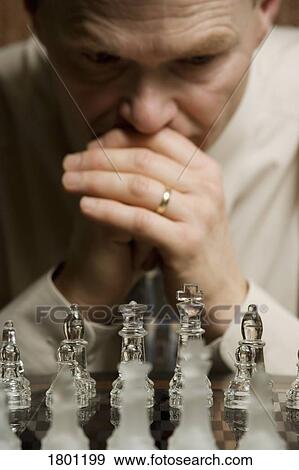 Stock Photo - Man concentrating on chess game. Fotosearch