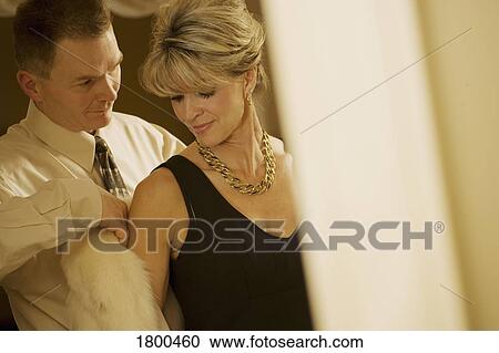 Stock Image - Man helping woman with her coat. Fotosearch
